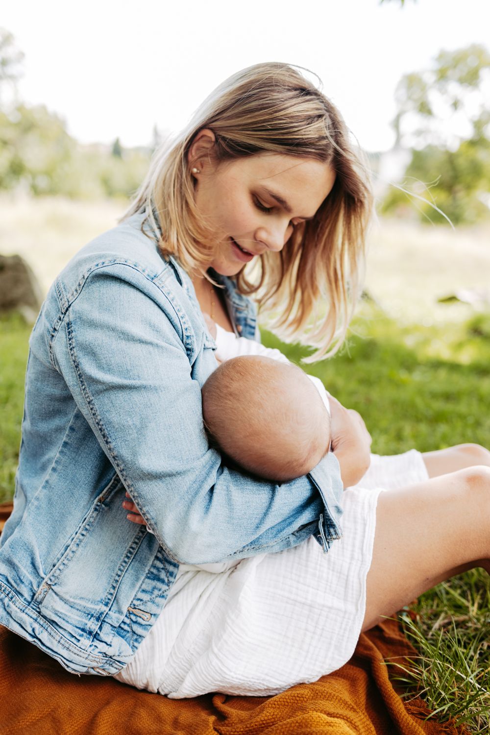 Franziska mit ihrem Baby auf dem Arm, draußen auf einer Wiese